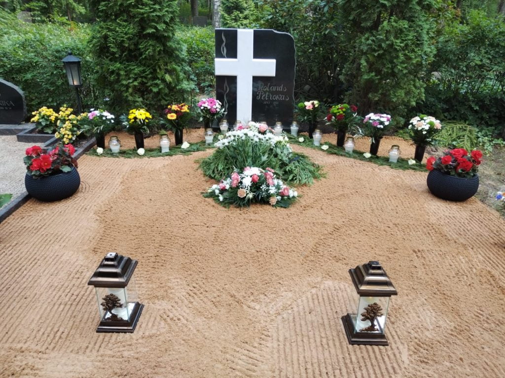 kapa dekorēšana ar ziediem un svecēm urnas apbedīšanai.