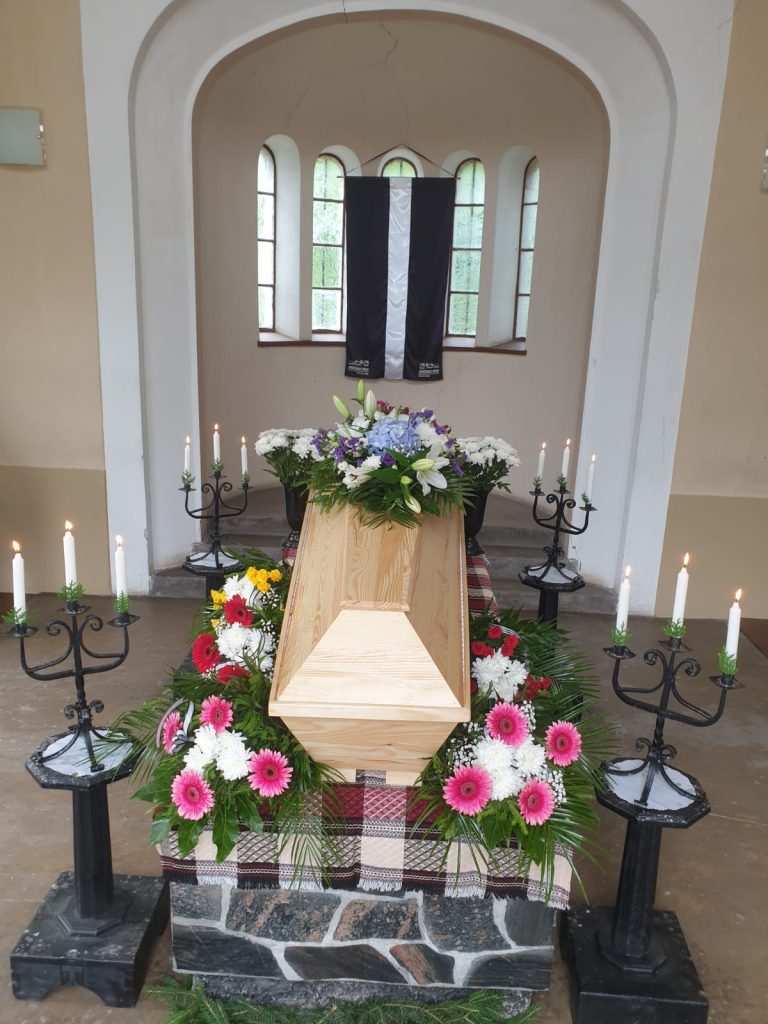 bēru ceremonijas noformējums ar ziediem un svecēm